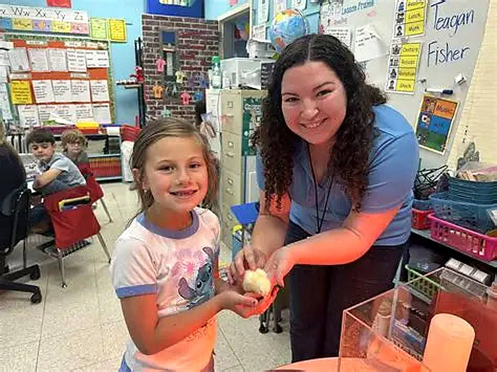 Teacher helping a student hold a newly hatched chick